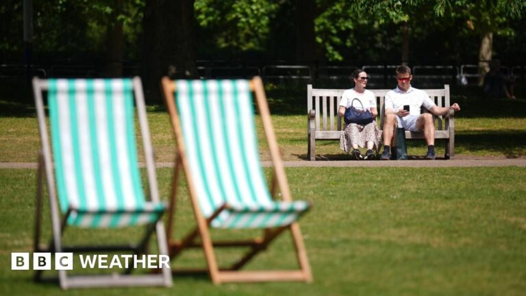A man and a woman sitting on a bench in a London park on the hottest day of the year so far